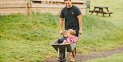 Hillside Glamping dad wheeling children in a wheelbarrow
