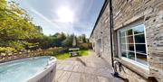 Hot tub on sandstone patio with holiday cottage on right