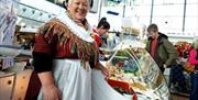 A lady wearing a traditional welsh dress for St David's Day in Swansea Market