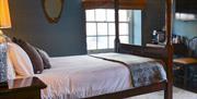 A grand four-poster bed in the centre of an elegant bedroom