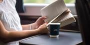 A woman reading with a coffee on a GWR train