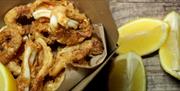 Bysgod wedi'u ffrio sydd ar gael i'w prynu o Gower Seafood Hut mewn cynwysyddion cludfwyd.