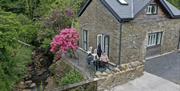 Riverside patio alongside holiday cottage with flowering rhododendron