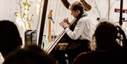Mission Gallery person playing harp as crowd watches