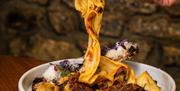 Plate of Short rib ragu bolognese. A stand is being lifted off the plate.