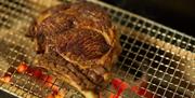 Rok Mumbles steak cooking on open grill