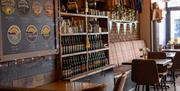 The Taproom Mumbles interior with tables and chairs, and a selection of bottled beer and merchandise available