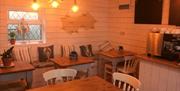 Y tu mewn i'r caffi gyda byrddau a chadeiriau pren.