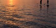 The Sup Hut paddle boarders on the sea with a sunset
