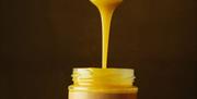 A jar of Gower Cottage Brownies' Blondie Butter with a spoon above dripping the product into the jar.