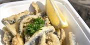 Bysgod wedi'u ffrio sydd ar gael i'w prynu o Gower Seafood Hut mewn cynwysyddion cludfwyd.